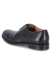 Schwarzer Lederschuh mit runder Spitze, Schnürverschluss und dezenten Nähten. Verfügt über eine glatte Textur und einen niedrigen Absatz.