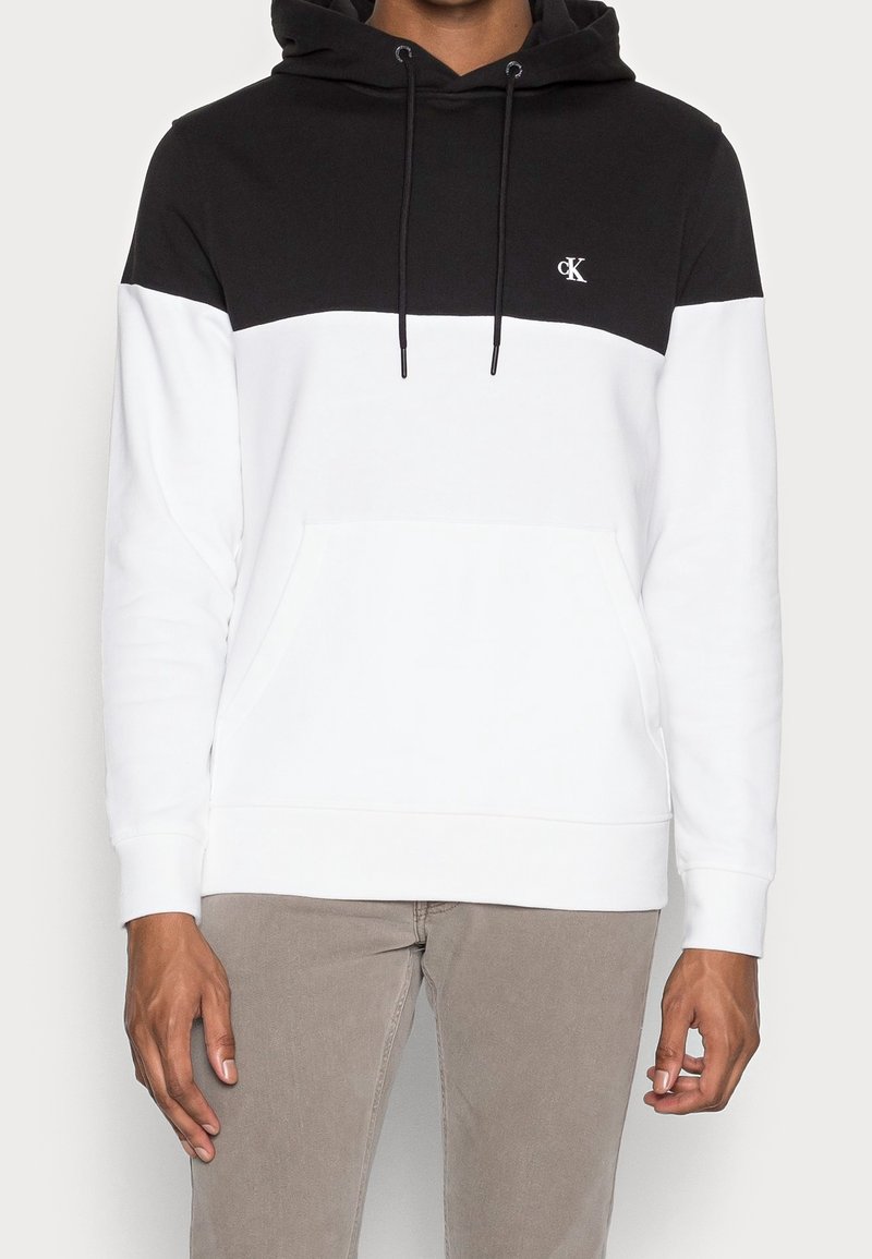 Schwarz-weiße Kapuzenjacke aus Baumwollmischung mit einem Design aus kontrastierenden Farbblöcken, frontaler Kängurutasche und einer verstellbaren Kapuze.