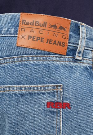 Jeans aus Denim mit einem beigefarbenen Lederpatch mit der Aufschrift "Red Bull Racing X Pepe Jeans." Verfügt über rote "RBR"-Stickerei und hellblaue Waschungen.