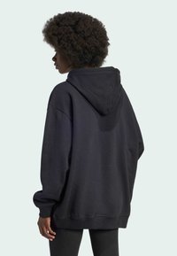 Svart oversized hettegenser med snor i hetta, ribbede mansjetter og kant, ekstra mykt stoff og en uformell, avslappet passform.