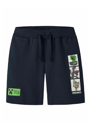 Short bleu marine avec cordon, patch logo Minecraft Creeper sur la jambe gauche et trois illustrations de personnages Minecraft sur la jambe droite.