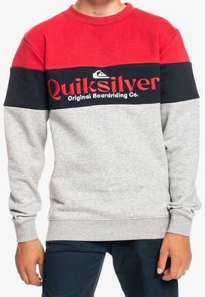 Sweatshirt coloré en blocs rouge, marine et gris avec un col rond et le logo "Quiksilver" en texte rouge vif. Matière en coton douce, manches longues.