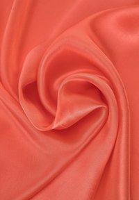 Tejido de color coral, textura suave, drapeado en suaves pliegues, con un ligero brillo, mostrando un color sólido sin patrones ni adornos.