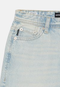 Pantaloni scurți din denim albastru deschis, cu croială extra largă, prevăzuți cu cusături contrastante, buzunare mari frontale și etichete de marcă pe talie.