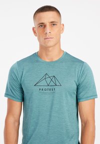 Teal korteblauwe t-shirt met korte mouwen, gemaakt van een lichtgewicht stof, met een zwart geometrisch bergontwerp en tekst op de voorkant.