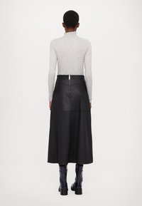 Schwarzer Midirock aus Leder mit glatter Textur, Reißverschluss hinten und Nahtdetails, kombiniert mit einem grauen Langarmshirt und dunkelblauen Stiefeln.