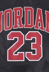 Tricou negru cu text mare „JORDAN” roșu și numărul „23”, cu cusături albe la contur și o textură netedă.