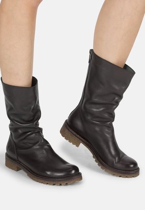 Botas de tobillo de cuero negro con un diseño arrugado, punta redonda y suela de goma texturizada. Cierre con cremallera en el lateral para un fácil uso.