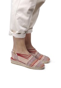 Espadrillas con una parte superiore in tessuto multicolore a righe nei toni di rosa, rosso e beige, con cinturini elasticizzati rossi e suola in juta.