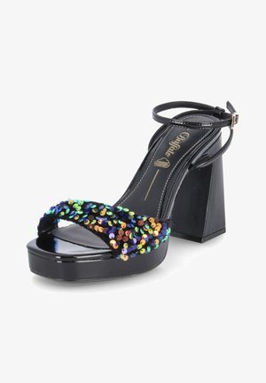 Musta korkokenkä, jossa on neliömäinen korko ja jonka päällä on monivärinen paljettinauha. Mutta kiiltävä lakattu pinta ja säädettävä nilkkahihna.