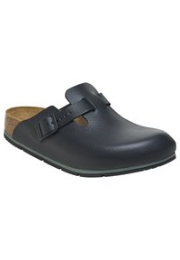 Black clogs with a smooth leather upper, natural cork insole, and adjustable strap. Rubber sole with a green accent around the edge.