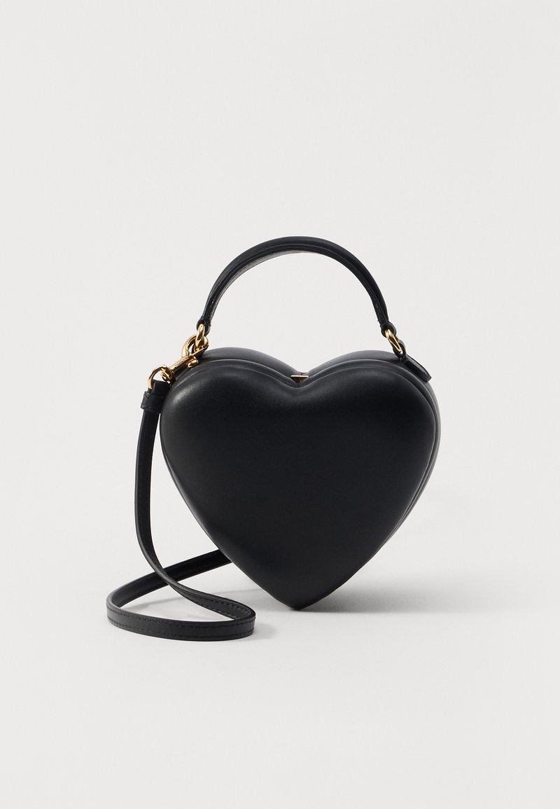Black heart-shaped bag made of smooth leather, featuring a top handle, detachable shoulder strap, and gold-tone hardware accents.