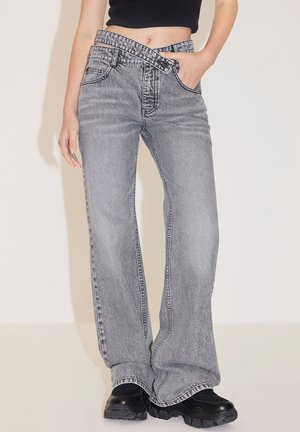 Gray flared jeans with a high waist, textured denim, five-pocket design, and contrasting stitching, paired with black chunky-soled shoes.