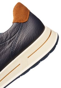 Baskets en cuir bleu marine avec semelle blanche texturée et accent talon en daim marron, vues de côté et de l'arrière.