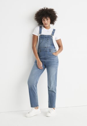 Denim salopettes met een relaxed fit, lichtblauwe kleur, voorzakken, verstelbare banden en gecombineerd met een wit t-shirt en witte sneakers.