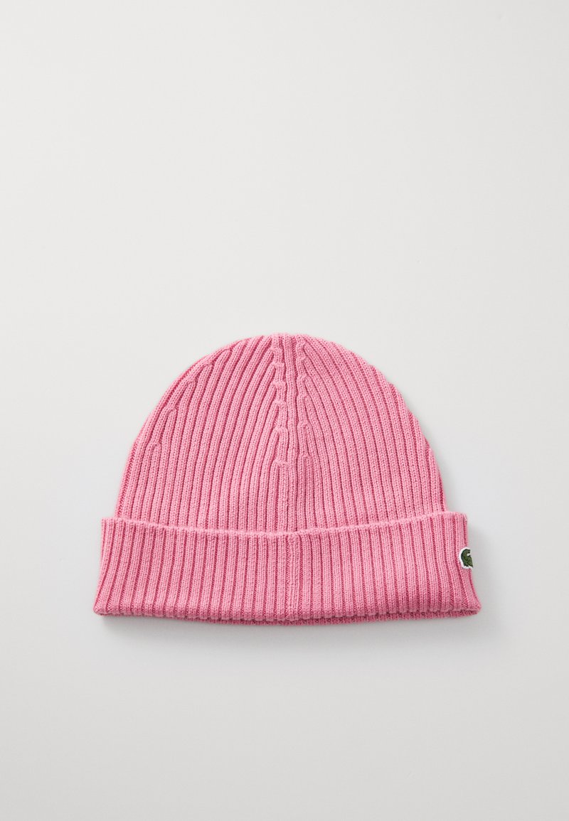 Różowa dziana czapka beanie z ribbowym wzorem, z zakładanym mankietem i małą zieloną łatką logo z boku. Gładki, elastyczny materiał.