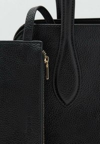 Borsa a mano in pelle nera granata con tasca con zip, hardware dorato e due manici arrotondati. Superficie texturizzata con cuciture visibili.