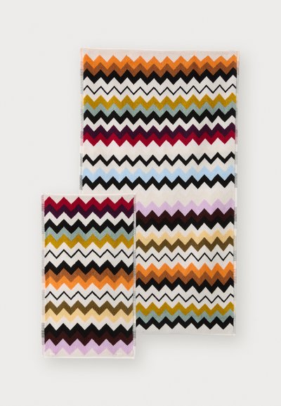 To håndklær med zigzag-mønster, i livlige farger som oransje, svart, rød og grønn. Begge er laget av mykt, teksturert stoff.