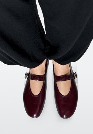 Burgundy leather Mary Jane shoes with a rounded toe, featuring a side buckle strap and cut-out design, viewed from above.
