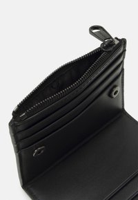 Portafoglio in pelle nera con scomparto con zip, multiple fessure per carte e chiusura con bottone in metallo. Caratterizza una texture liscia e un design minimalista.