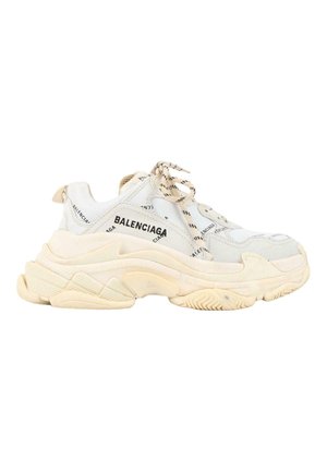 Bielono beżowy masywny sneaker Balenciaga z grubą podeszwą oraz czarnymi wzorami logo z tekstem na wierzchu i sznurowadłach.
