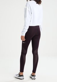 Ljusblå kortärmad sweatshirt med lång ärm, matchad med mörklila leggings med meshdetaljer och en liten vit Nike-logga.