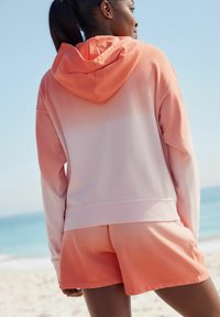 Hoody en shorts in een verloop van zachtroze naar koraal. Gemaakt van lichtgewicht stof met een losse fit en ribgebreide randen.