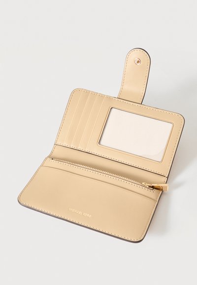 Portefeuille en cuir beige avec fermeture pression, comprenant des emplacements pour cartes, une fenêtre transparente pour carte d’identité et un compartiment zippé.