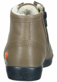 Bottines en cuir marron avec une doublure en peluche, fermeture éclair sur le côté et semelle en caoutchouc noire. Présente un petit accent orange au niveau du talon.