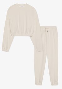 Beige Loungewear-Set bestehend aus einem kurzärmeligen Oberteil mit elastischem Saum und passenden Hosen mit elastischem Bund und Kordelzug.