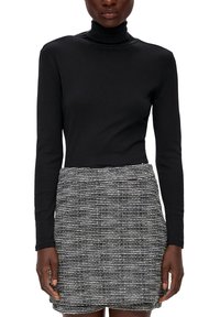 Svart polokrage topp kombinerad med en strukturerad, mönstrad svart-vit kjol med horisontella ränder. Slät tyg med figursydd silhuett.