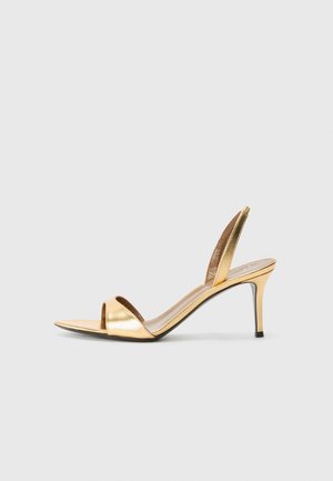 Gold metallic slingback sandal with open-toe design, slender heel, and smooth shiny texture. Features elegant stitching and minimalistic style.