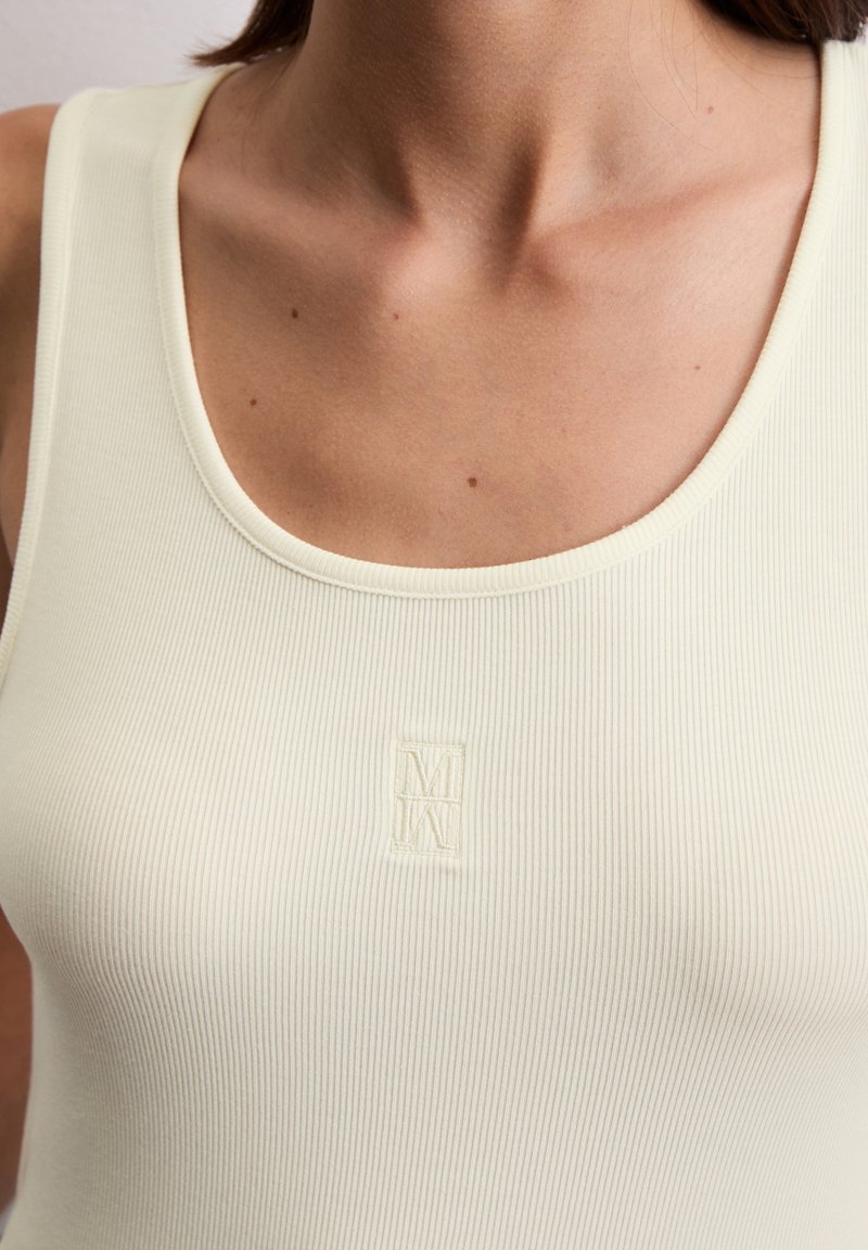 Jasnożółty, prążkowany top bez rękawów z okrągłym dekoltem i małym haftowanym logo, charakteryzujący się gładką teksturą i dopasowanym krojem.