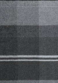 Szara wełniana kołdra o różnorodnych fakturach, w tym wzory w szachownicę i rybią łuskę, z naprzemiennie jasnoszarymi i ciemnoszarymi paskami.