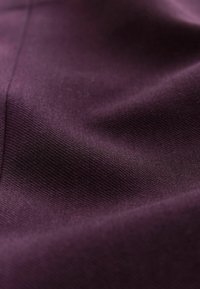 Tisă de culoare violet închis cu o textură netedă, prezentând modele țesute subtile și un ușor luciu, reflectând lumina într-un mod delicat.