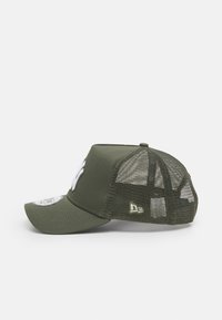Casquette vert olive avec un front solide, dos en mesh et visière incurvée. Présente un logo brodé en blanc et une petite étiquette de marque verte sur le côté.