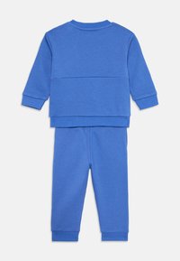 Set di cotone a due pezzi di colore blu brillante, composto da una felpa a girocollo con maniche lunghe e pantaloni da tuta abbinati con polsini a coste.
