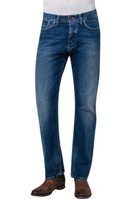 Vaqueros de denim azul con un corte recto, lavado desgastado, trabillas para el cinturón, diseño de cinco bolsillos y costuras en contraste, combinados con botas marrones.