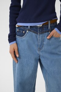Light blue denim jeans with a relaxed fit, featuring subtle contrast stitching, classic five-pocket design, and a brown leather belt.