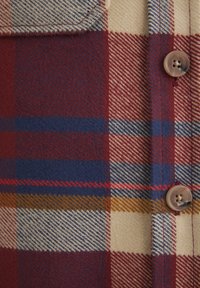 Wollhemd mit einem karierten Muster in Rot, Blau und Beige, einem strukturierten Finish und einer braunen Knopfdetaillierung an der Knopfleiste.