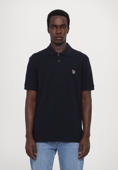 Polo-shirt bleu marine en coton, doté d'un col, d'une patte de boutonnage à trois boutons et d'un petit logo brodé sur la poitrine.