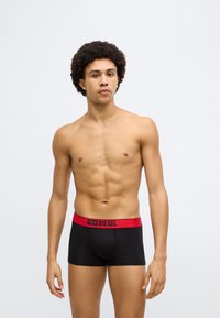 Fekete boxeralsó piros elasztikus derékrésszel, amelyen a "DIESEL" logó található. Az anyag sima hatású, és testhezálló fazonú.