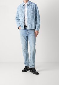 Light blue checkered denim jacket, white shirt, light blue jeans, and black shoes with chunky soles. The jacket features two chest pockets.