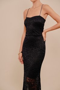 Μαύρο δαντελένιο μάξι φόρεμα με λεπτές τιράντες, που διαθέτει περίπλοκα σχέδια, εφαρμοστή σιλουέτα και διαφάνεια στο κάτω μέρος.