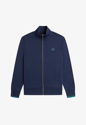 Veste zippée bleu marine avec col montant, poches latérales, poignets côtelés avec rayures vertes et petit logo laurier turquoise sur la poitrine.