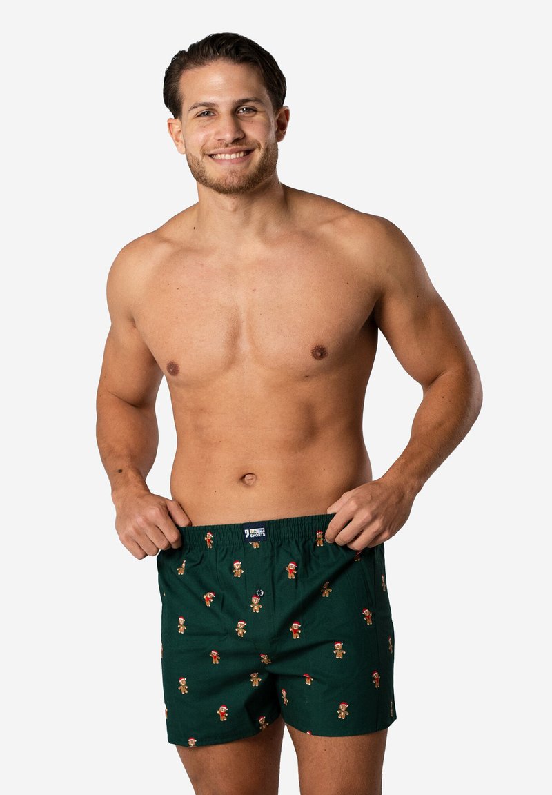 Groene katoenen boxershorts met een patroon van peperkoekmannetjes die een kerstmanmuts dragen. Elastische tailleband voor comfort.