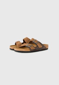 Brown suede and leather sandals with two adjustable metal buckles and cork footbeds on a white background.