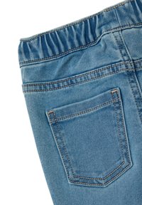 Los pantalones de mezclilla azules cuentan con una cinturilla elástica, un bolsillo trasero y costuras contrastantes a lo largo de las costuras. Textura suave y ligeramente deslavada.