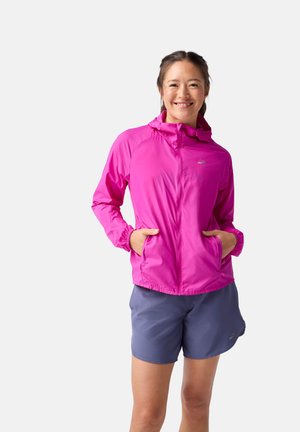 Veste de course légère rose avec capuche, fermeture éclair à l'avant, poignets élastiques et poches, associée à un short bleu. Texture lisse et design sportif.