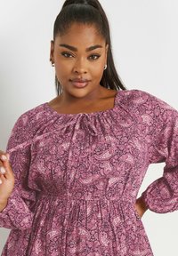 Lila paisley-kuosiset mekko, jossa on kerrottu pääntie ja pitkät hihat, elastinen vyötärö ja rento tekstuuri.